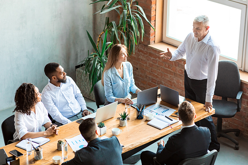 Employer giving speech on meeting with employees sitting in office